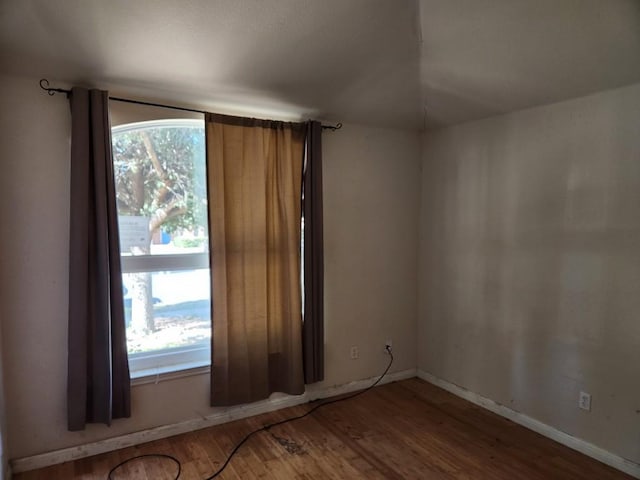 empty room featuring baseboards and wood finished floors