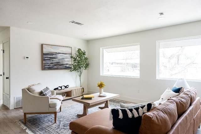 living area with baseboards, visible vents, and wood finished floors