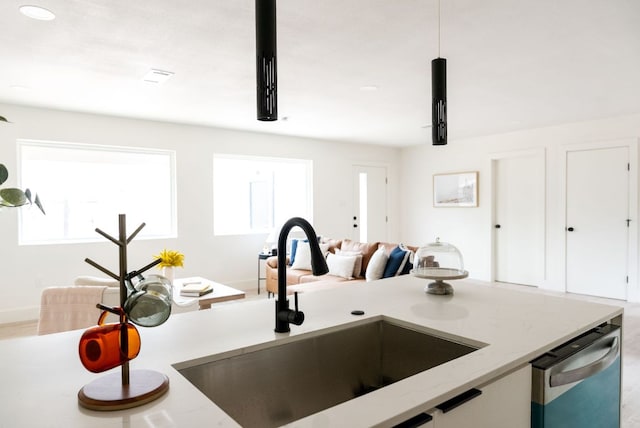 kitchen featuring white cabinets, a sink, dishwasher, and light stone countertops