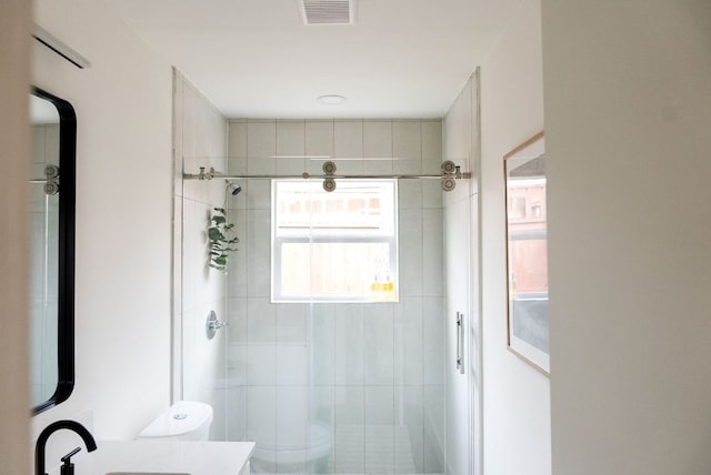 bathroom with a stall shower, visible vents, vanity, and toilet