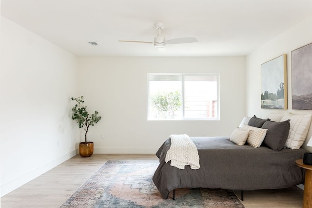 bedroom with ceiling fan, wood finished floors, visible vents, and baseboards