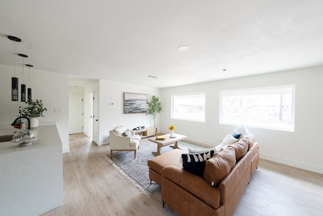 living area featuring light wood-style floors, visible vents, and baseboards