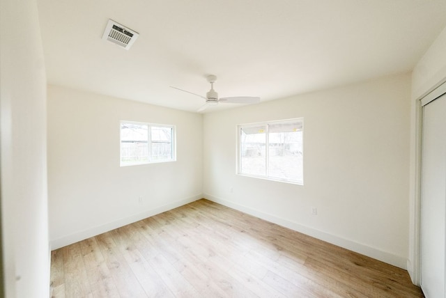 spare room featuring a ceiling fan, visible vents, baseboards, and wood finished floors