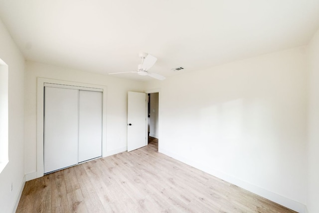 unfurnished bedroom featuring light wood finished floors, a closet, visible vents, and baseboards