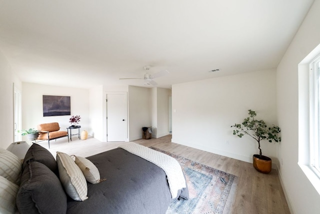 bedroom with light wood-style floors, visible vents, ceiling fan, and baseboards