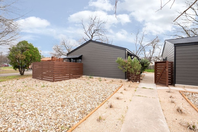 view of home's exterior with an outbuilding and fence