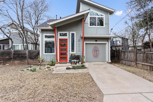 view of front of property with concrete driveway, board and batten siding, an attached garage, and fence