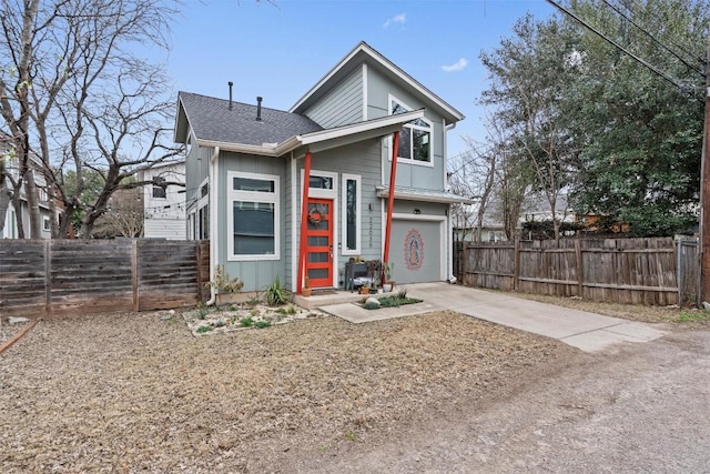 view of front of house with a garage, concrete driveway, fence, and board and batten siding