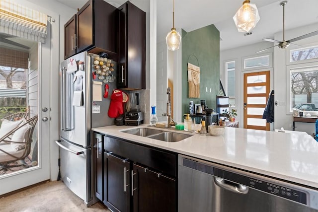 kitchen with pendant lighting, stainless steel appliances, a sink, and light countertops