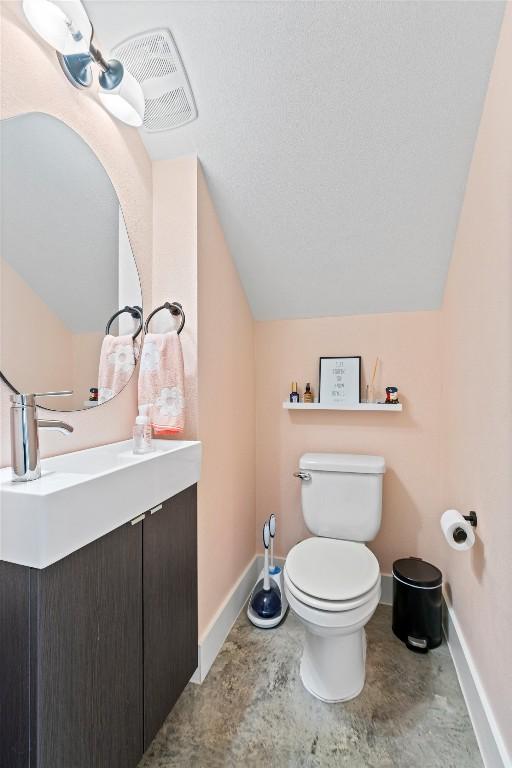 bathroom featuring toilet, baseboards, vaulted ceiling, and vanity