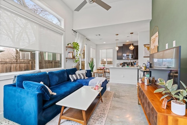 living room with ceiling fan, concrete floors, and visible vents