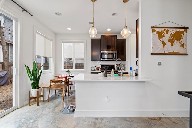 kitchen with stainless steel appliances, concrete floors, dark brown cabinets, light countertops, and backsplash