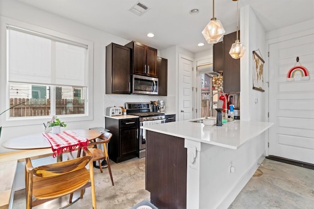 kitchen with appliances with stainless steel finishes, visible vents, a sink, and concrete flooring