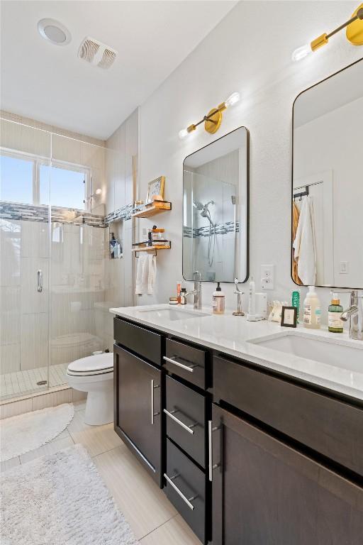 bathroom with visible vents, a sink, a shower stall, and toilet