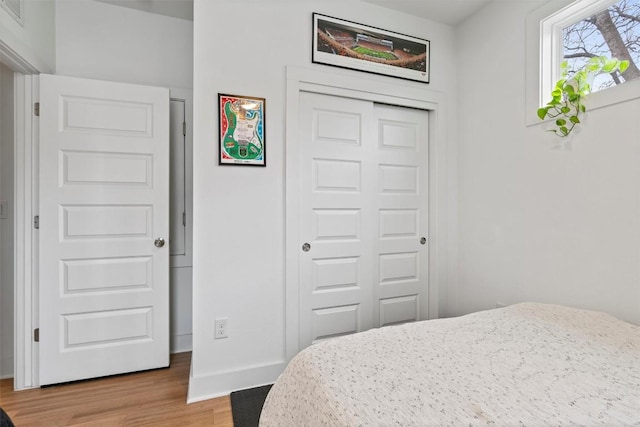 bedroom with light wood-style floors, a closet, and baseboards