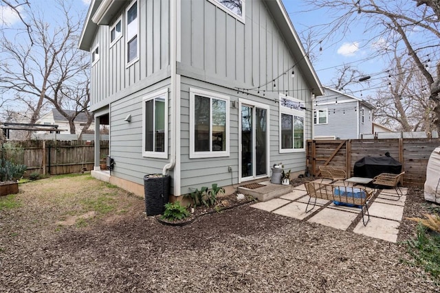 back of house with entry steps, a fenced backyard, board and batten siding, and a patio