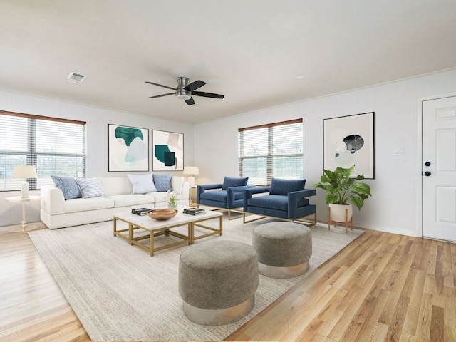 living area with a ceiling fan, a wealth of natural light, visible vents, and wood finished floors