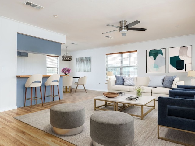 living area with a ceiling fan, visible vents, and wood finished floors