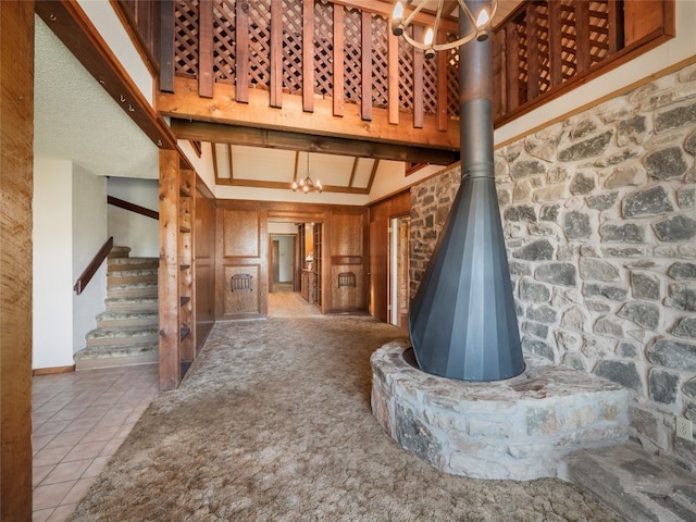 805 Wanta Hideaway, Spicewood, TX 78669 - unfurnished living room with a chandelier, stairway, tile patterned flooring, a high ceiling, and a wood stove
