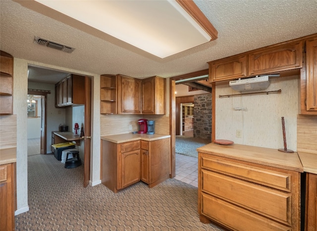 805 Wanta Hideaway, Spicewood, TX 78669 - kitchen featuring light countertops, brown cabinetry, a textured ceiling, open shelves, and light flooring