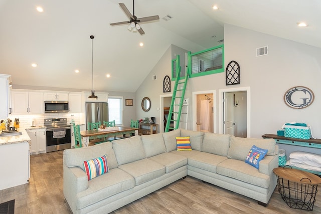 living area with ceiling fan, light wood finished floors, visible vents, and recessed lighting