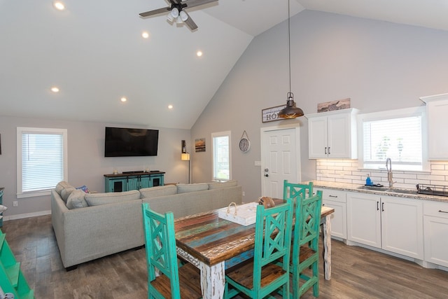 dining room with a ceiling fan, a healthy amount of sunlight, high vaulted ceiling, and wood finished floors