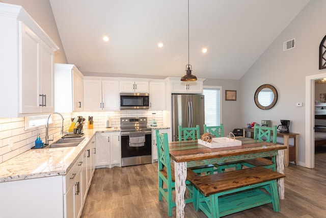 kitchen with visible vents, light stone countertops, stainless steel appliances, white cabinetry, and a sink