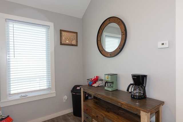 interior space featuring dark wood-style flooring, vaulted ceiling, and baseboards