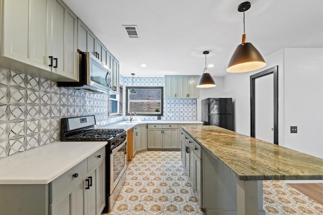 2702 S 2nd St Unit 1 & 2, Austin, TX 78704 - kitchen with appliances with stainless steel finishes, a kitchen island, tasteful backsplash, gray cabinetry, and decorative light fixtures