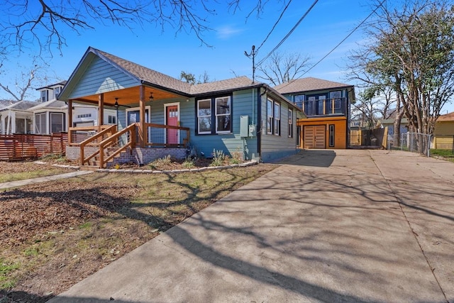 view of front of home with covered porch, driveway, a balcony, and fence