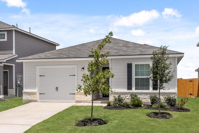 view of front facade with a garage, fence, concrete driveway, roof with shingles, and a front yard