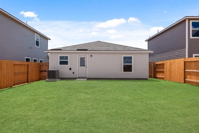 back of house with central AC unit, a lawn, and a fenced backyard