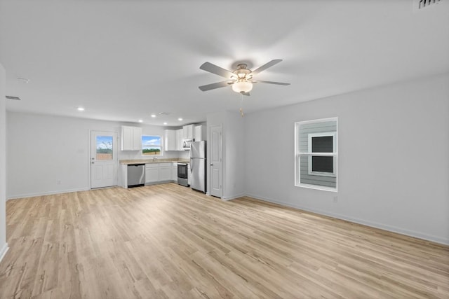 unfurnished living room with light wood-style flooring, visible vents, baseboards, and ceiling fan