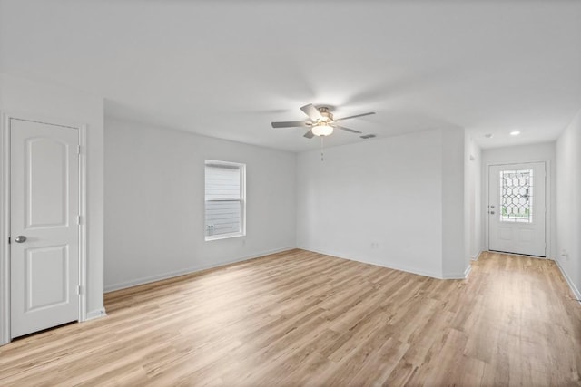 empty room featuring visible vents, light wood-type flooring, a ceiling fan, and baseboards