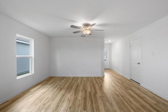 unfurnished room with light wood-style floors, plenty of natural light, baseboards, and a ceiling fan