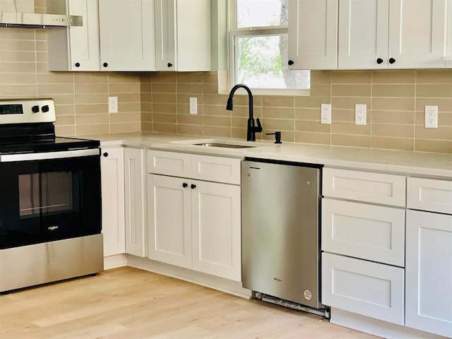 kitchen featuring light countertops, appliances with stainless steel finishes, a sink, and under cabinet range hood