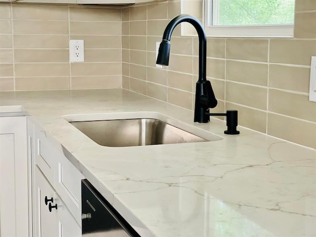 room details with backsplash, a sink, white cabinetry, and light stone countertops