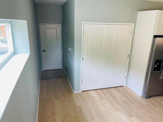 corridor with light wood-style floors and baseboards