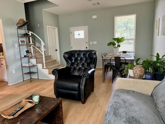 living area featuring light wood-type flooring, visible vents, and stairs