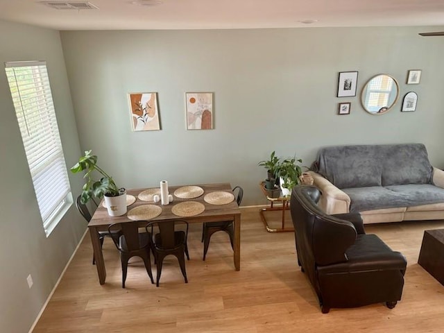 living area with light wood-type flooring, visible vents, and baseboards