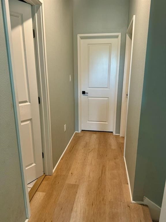 corridor featuring light wood-style flooring and baseboards