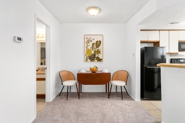 living area featuring a textured ceiling, light tile patterned flooring, light carpet, visible vents, and baseboards