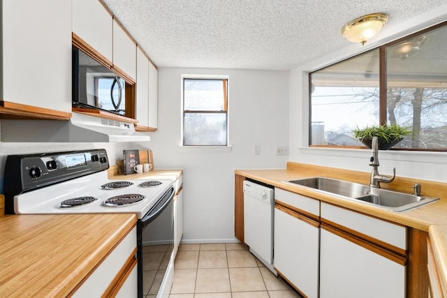 kitchen featuring black microwave, white dishwasher, a sink, light countertops, and electric range oven