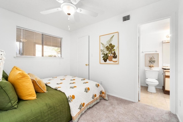 tiled bedroom featuring carpet flooring, visible vents, baseboards, a ceiling fan, and ensuite bath