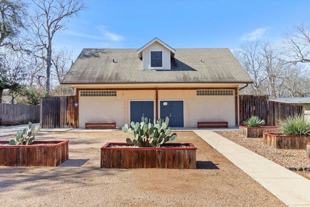 view of front of home with a shingled roof, fence, and stucco siding