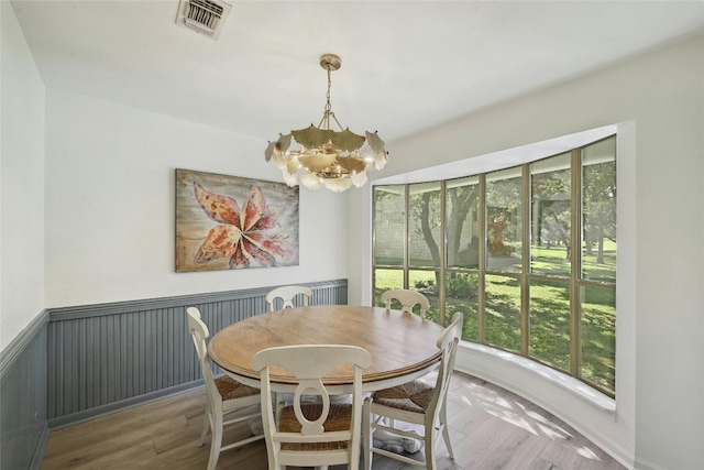 608 Sombrero Dr, Horseshoe Bay, TX 78657 - dining area featuring wainscoting, wood finished floors, visible vents, and a notable chandelier