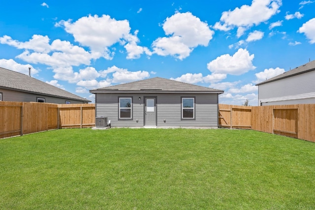 rear view of house featuring central air condition unit, a fenced backyard, and a yard