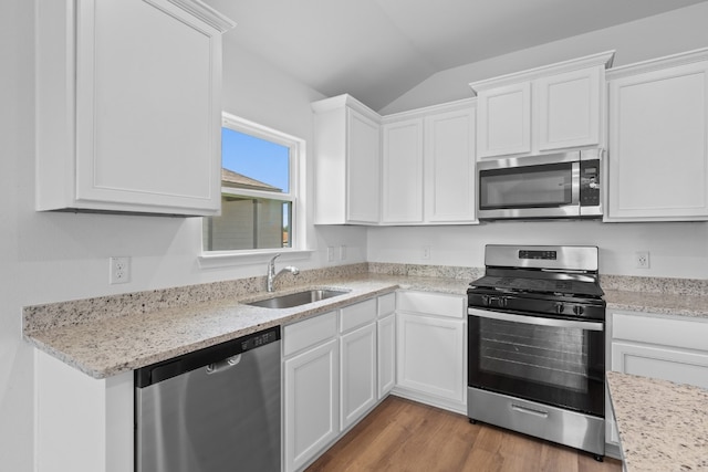 kitchen with lofted ceiling, stainless steel appliances, a sink, light wood-style floors, and white cabinets