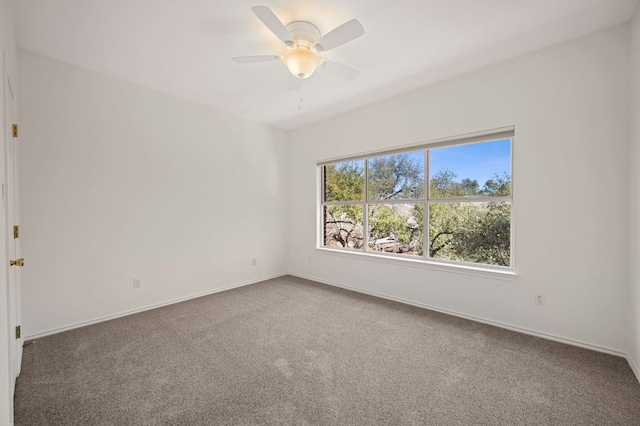 empty room with carpet, a ceiling fan, and baseboards