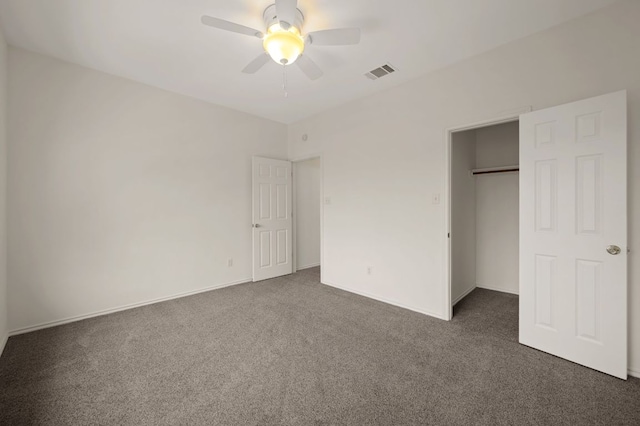 unfurnished bedroom with dark colored carpet, a closet, visible vents, and a ceiling fan